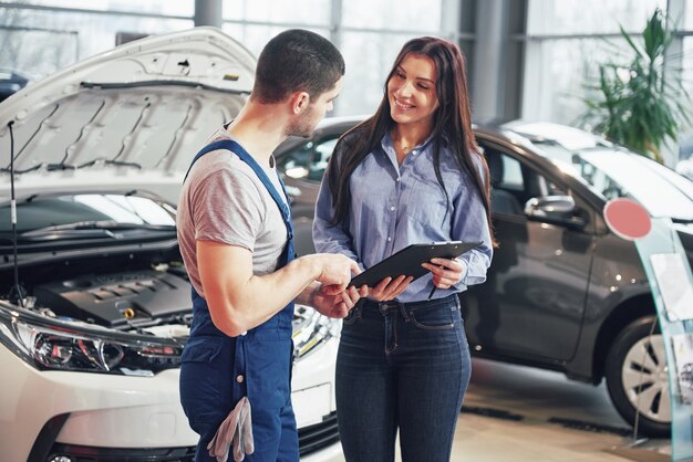 Ein Mann Mechaniker und Frau Kunde diskutieren Reparaturen an ihrem Fahrzeug durchgeführt