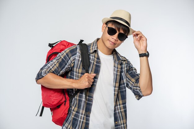 Ein Mann mit Brille geht auf Reisen, trägt einen Hut und einen Rucksack