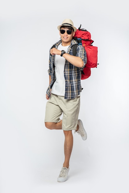 Ein Mann mit Brille geht auf Reisen, trägt einen Hut und einen Rucksack