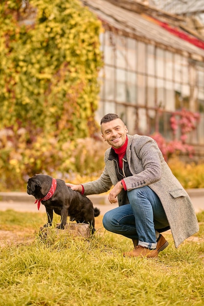 Ein Mann mit einem schwarzen Hund im Herbstpark