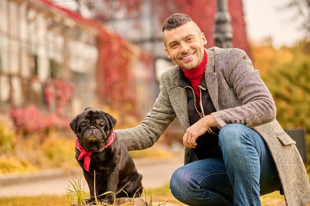 Ein Mann mit einem schwarzen Hund im Herbstpark