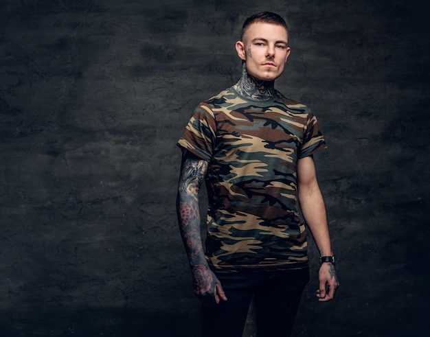 Kostenloses Foto ein mann mit tätowierungen an hals, gesicht und armen, bekleidet mit einem camouflage-t-shirt.