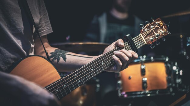 Ein Mann spielt eine akustische Gitarre in der dunklen Nahaufnahme