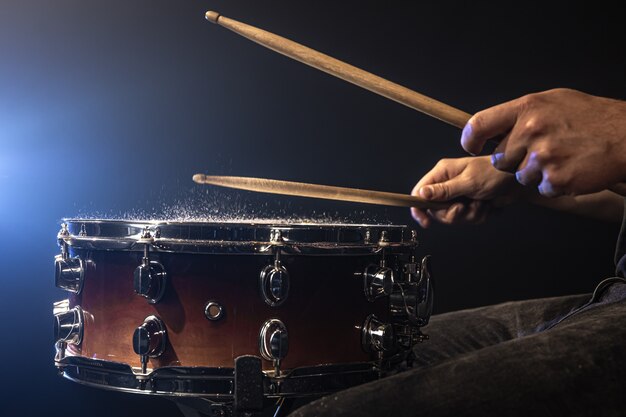 Ein Mann spielt mit Drumsticks auf einer Snare-Drum mit Spritzwasser.