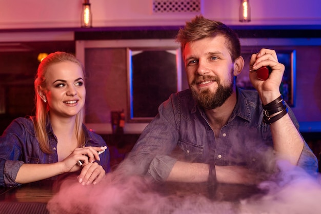 Kostenloses Foto ein mann und eine frau rauchen elektronische zigarette in einer vape-bar.