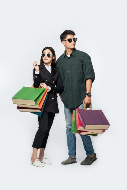 Ein Mann und eine Frau trugen eine Brille und trugen viele Papiertüten zum Einkaufen