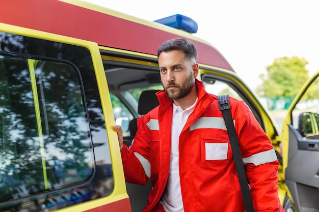 Ein Mitarbeiter des Krankenwagens kommt mit seinem Notfallrucksack und seinem Vitalzeichenmonitor aus dem hinteren Teil eines Krankenwagens