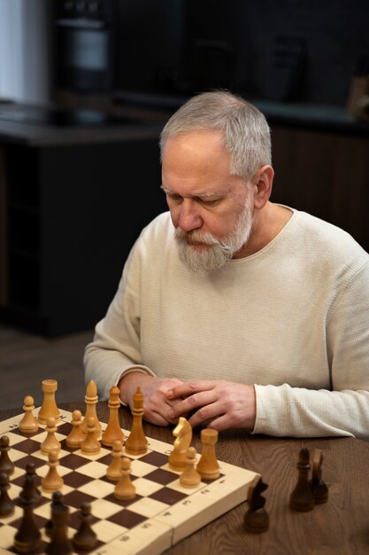 Ein mittelgroßer alter Mann spielt Schach.