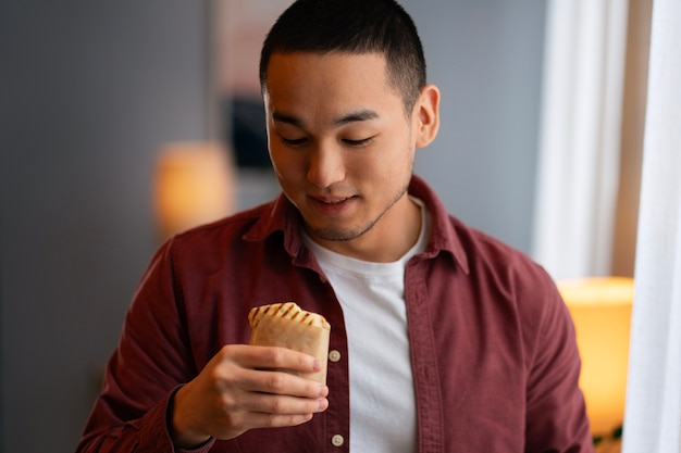 Kostenloses Foto ein mittelgroßer mann mit einem in papier eingewickelten sandwich