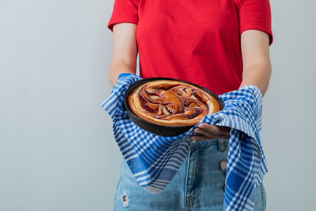 Ein Modell, das einen süßen Kuchen in einer schwarzen Pfanne hält