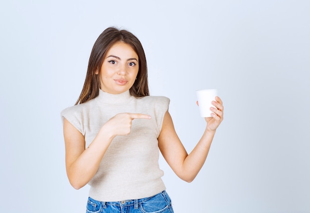 Ein Modell der jungen Frau, das auf einen Plastikbecher zeigt.