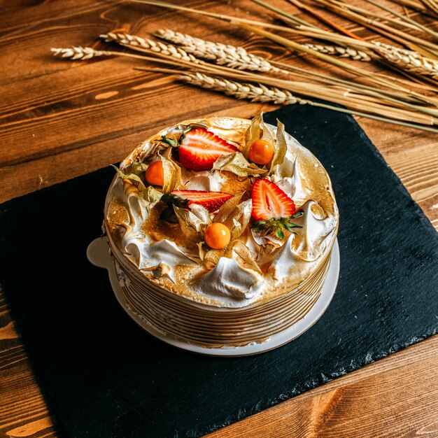 Ein Obstkuchen mit Draufsicht, köstlich dekoriert mit geschnittenen Erdbeeren rund um weiße Platte