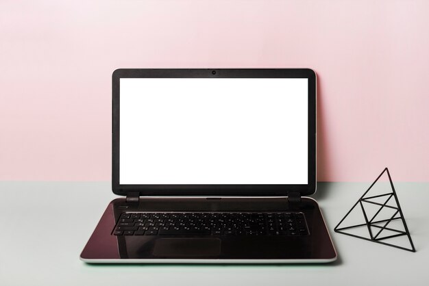 Ein offener Laptop mit leerem weißem Bildschirm gegen rosa Hintergrund