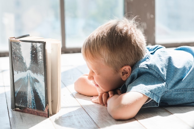 Kostenloses Foto ein offenes buch vor einem jungen, der seine augen schließt