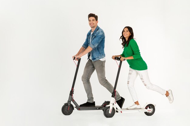 Ein Paar, das auf einem elektrischen Tretroller reitet, isoliert auf weißem Studiohintergrund