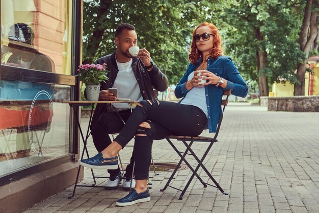 Ein Paar, das Kaffee trinkt und in der Nähe des Cafés sitzt. Draußen bei einem Date.