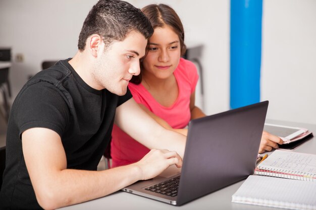 Ein paar hispanische Teenager studieren und benutzen gemeinsam einen Laptop in der Schule