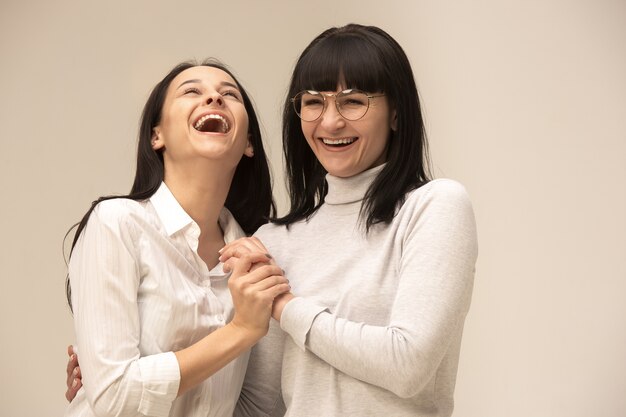 Ein Porträt einer glücklichen Mutter und Tochter im Studio auf grau