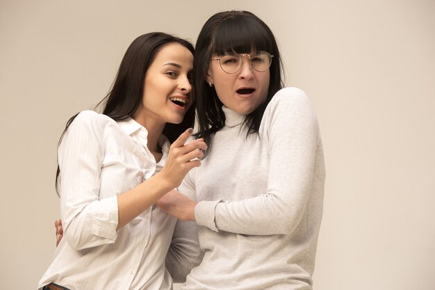 Ein Porträt einer glücklichen Mutter und Tochter im Studio auf grauem Hintergrund. Konzept der menschlichen positiven Emotionen und Gesichtsausdrücke