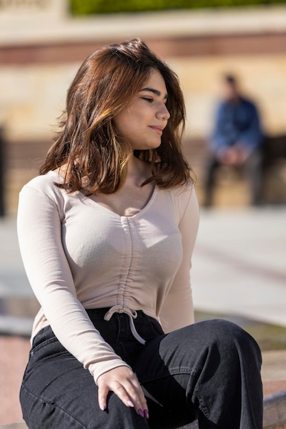 Ein Porträt eines jungen schönen Mädchens, das im Park unter der Sonne sitzt. Hochwertiges Foto