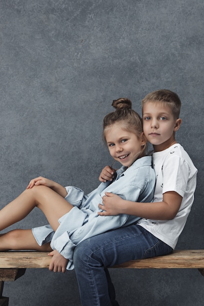 Ein Porträt eines kleinen Mädchens und eines Jungen an der grauen Wand