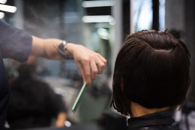 Ein professioneller Friseur macht einen Kundenhaarschnitt. Das Mädchen sitzt in einer Maske in Schönheit im Salon