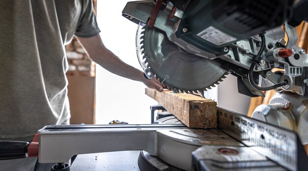 Ein professioneller Tischler arbeitet mit einer Kreissäge Gehrungssäge in einer Werkstatt.