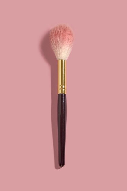 Ein Puder-Make-up-Rouge-Pinsel auf rosa Hintergrund