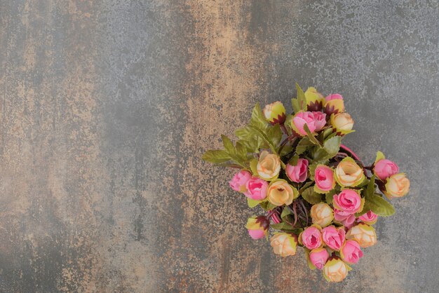 Ein rosa Eimer mit Blumenstrauß auf Marmoroberfläche.