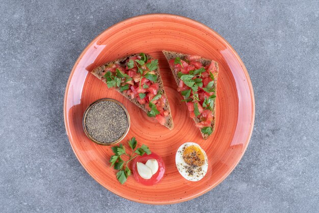 Ein roter Teller mit gekochtem Ei und Toast. Hochwertiges Foto