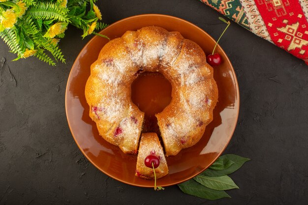 Ein runder Kirschkuchen der Draufsicht innerhalb des braunen Tellers auf dem dunklen Tischkuchenkekszuckersüß