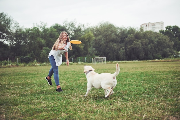 Ein schönes Mädchen, das mit ihrem geliebten Hund im Park spielt.