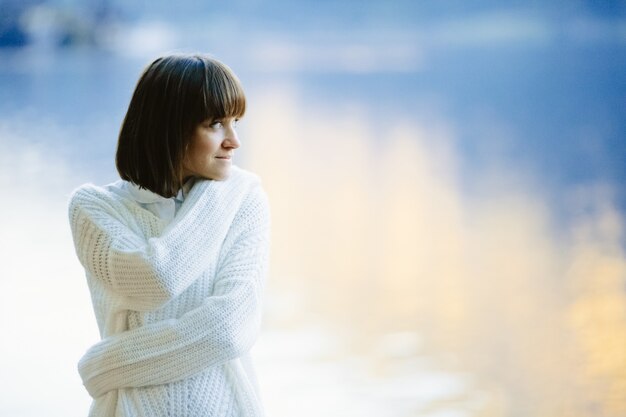 Ein schönes Mädchen in einem weißen Pullover lächelt