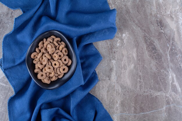 Ein schwarzer Teller mit gesunden Schokoladen-Müsli-Ringen zum Frühstück.