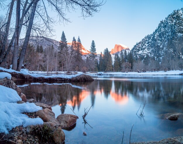 Ein See, umgeben von Felsen, Bäumen und Bergen in Yosemite im Winter