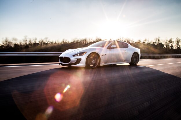 Ein silberner Hochgeschwindigkeitssportwagen, der auf der Autobahn im sonnigen Wetter fährt.