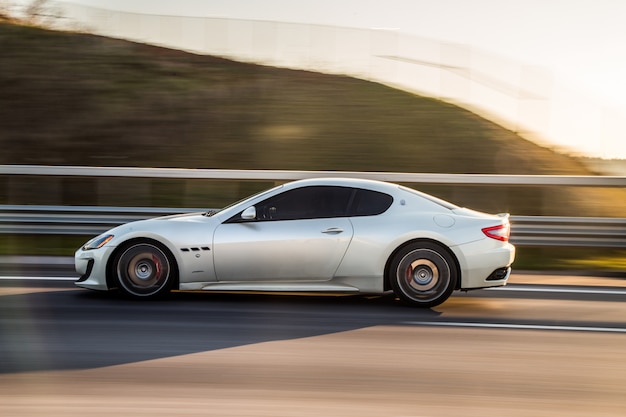 Ein silbernes Sportcoupé, das in die Landstraße fährt.