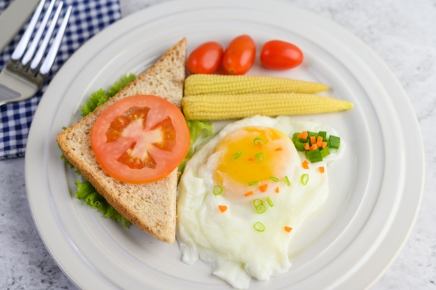 Kostenloses Foto ein spiegelei, das auf einem toast liegt, gekrönt mit pfeffersamen mit karotten, babymais und frühlingszwiebeln.