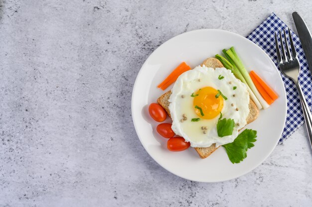 Ein Spiegelei, das auf einem Toast liegt und mit Pfeffersamen mit Karotten und Frühlingszwiebeln belegt ist.