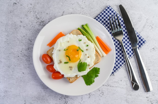 Ein Spiegelei, das auf einem Toast liegt und mit Pfeffersamen mit Karotten und Frühlingszwiebeln belegt ist.