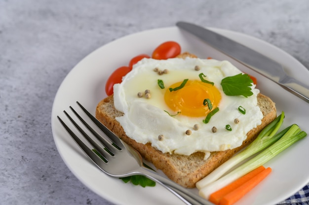 Ein Spiegelei, das auf einem Toast liegt und mit Pfeffersamen mit Karotten und Frühlingszwiebeln belegt ist.