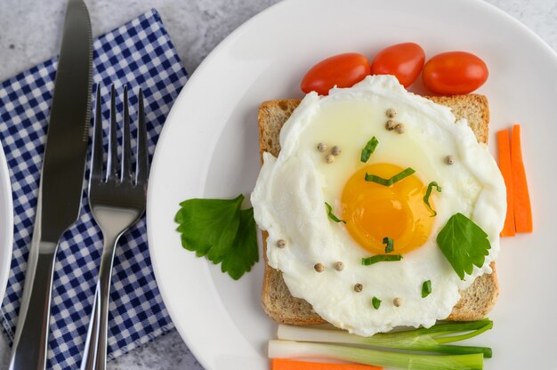 Ein Spiegelei, das auf einem Toast liegt und mit Pfeffersamen mit Karotten und Frühlingszwiebeln belegt ist.