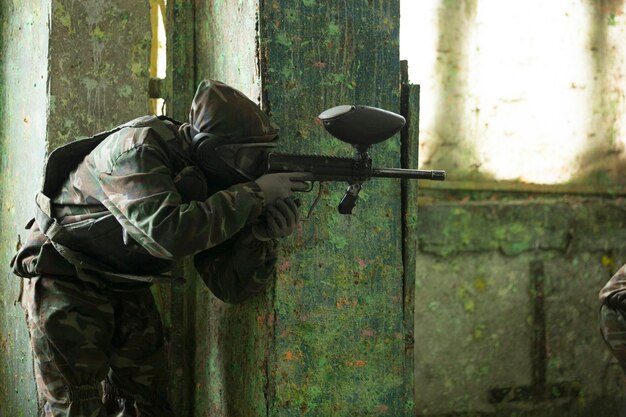 Ein Spieler, der Paintballspiel mit einer Waffe spielt. Hochwertiges Foto