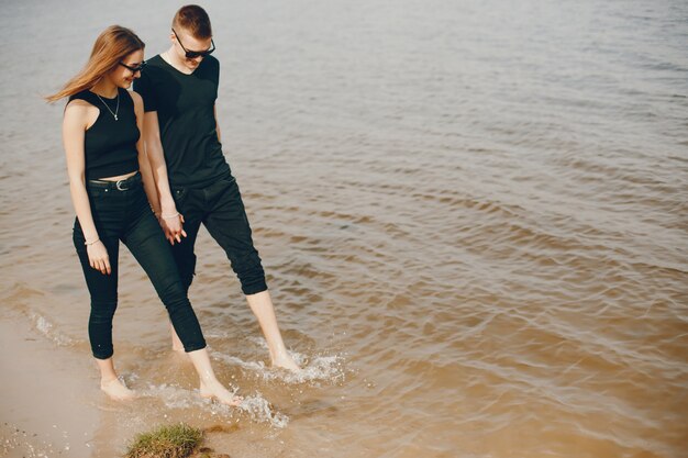 Ein stilvolles und schönes Paar in schwarzer Kleidung verbringt eine schöne Zeit am Strand