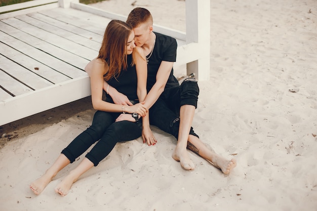 Ein stilvolles und schönes Paar in schwarzer Kleidung verbringt eine schöne Zeit am Strand