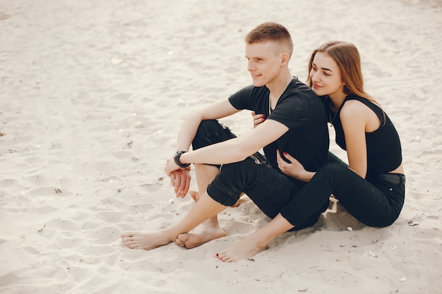 Ein stilvolles und schönes Paar in schwarzer Kleidung verbringt eine schöne Zeit am Strand