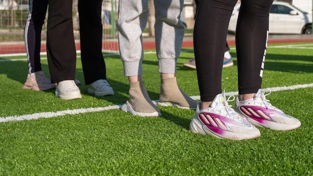 Ein Strahl von Frauenbeinen mit Turnschuhen bereit, sich auf dem Rasen körperlich zu betätigen