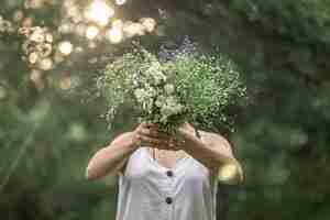 Kostenloses Foto ein strauß wilder blumen in den händen eines mädchens im wald.