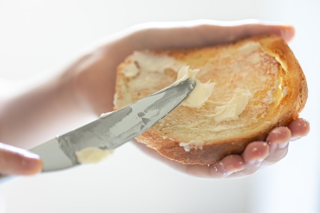 Ein Stück Brot mit Butter in der Hand einer Frau