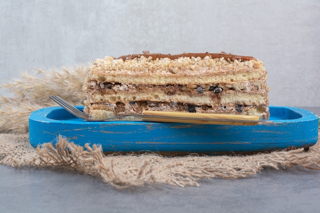 Kostenloses Foto ein stück cremiger kuchen auf blauem teller mit gabel.